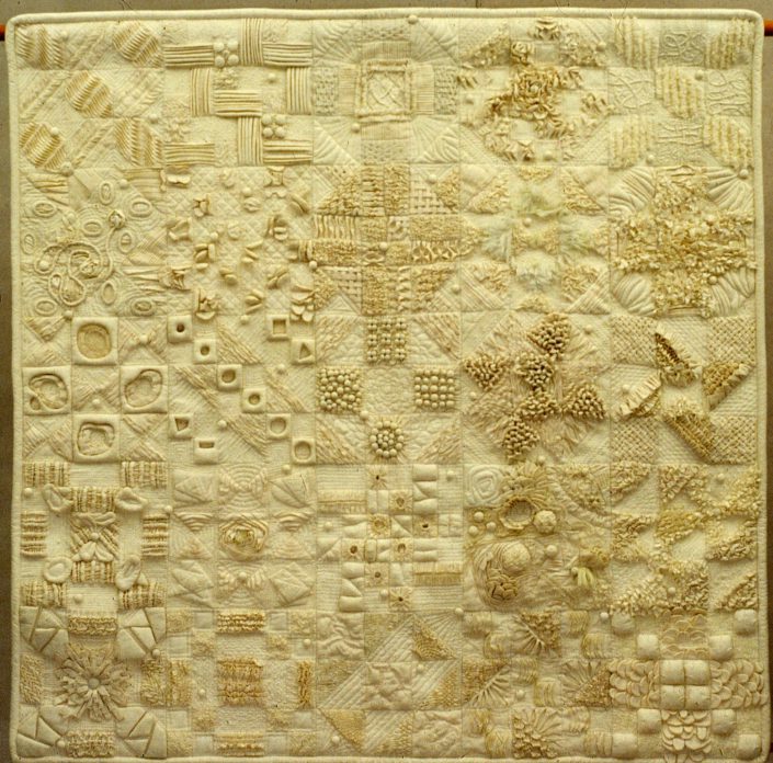 A cream-colored fabric with various 3D shapes sewn on it.