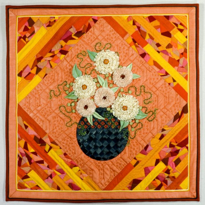 A quilt with flowers in it on top of orange and yellow.